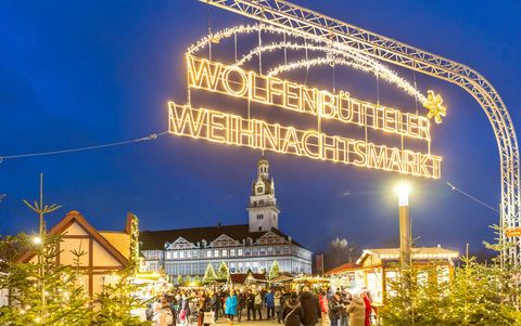 Leuchtender Schriftzug Wolfenbütteler Weihnachtsmarkt überspannt den Eingangsbereich zu einem stimmungsvollen Markt