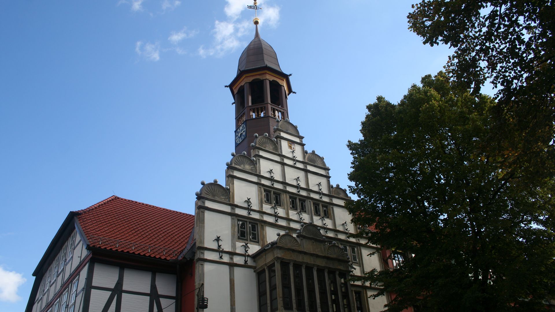 Historisches Gebäude in Nienburg mit markantem Turm und verziertem Fachwerk im Vordergrund.