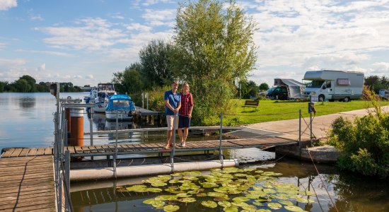 Een echtpaar staat op een steiger aan de rivier de Weser, op de achtergrond een camperplaats, © TMN / Markus Tiemann