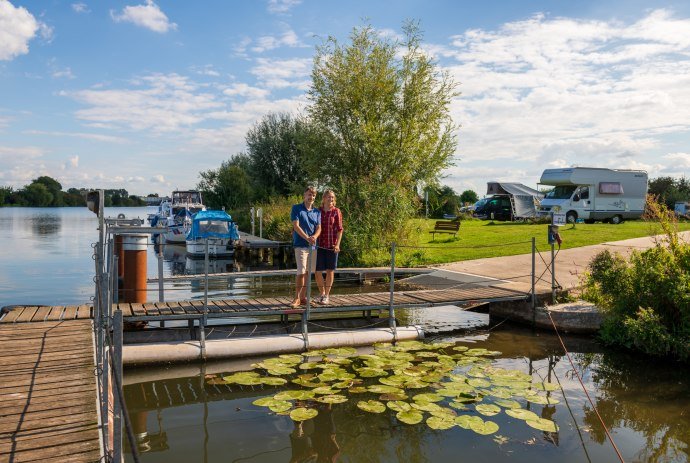 Een echtpaar staat op een steiger aan de rivier de Weser, op de achtergrond een camperplaats, © TMN / Markus Tiemann