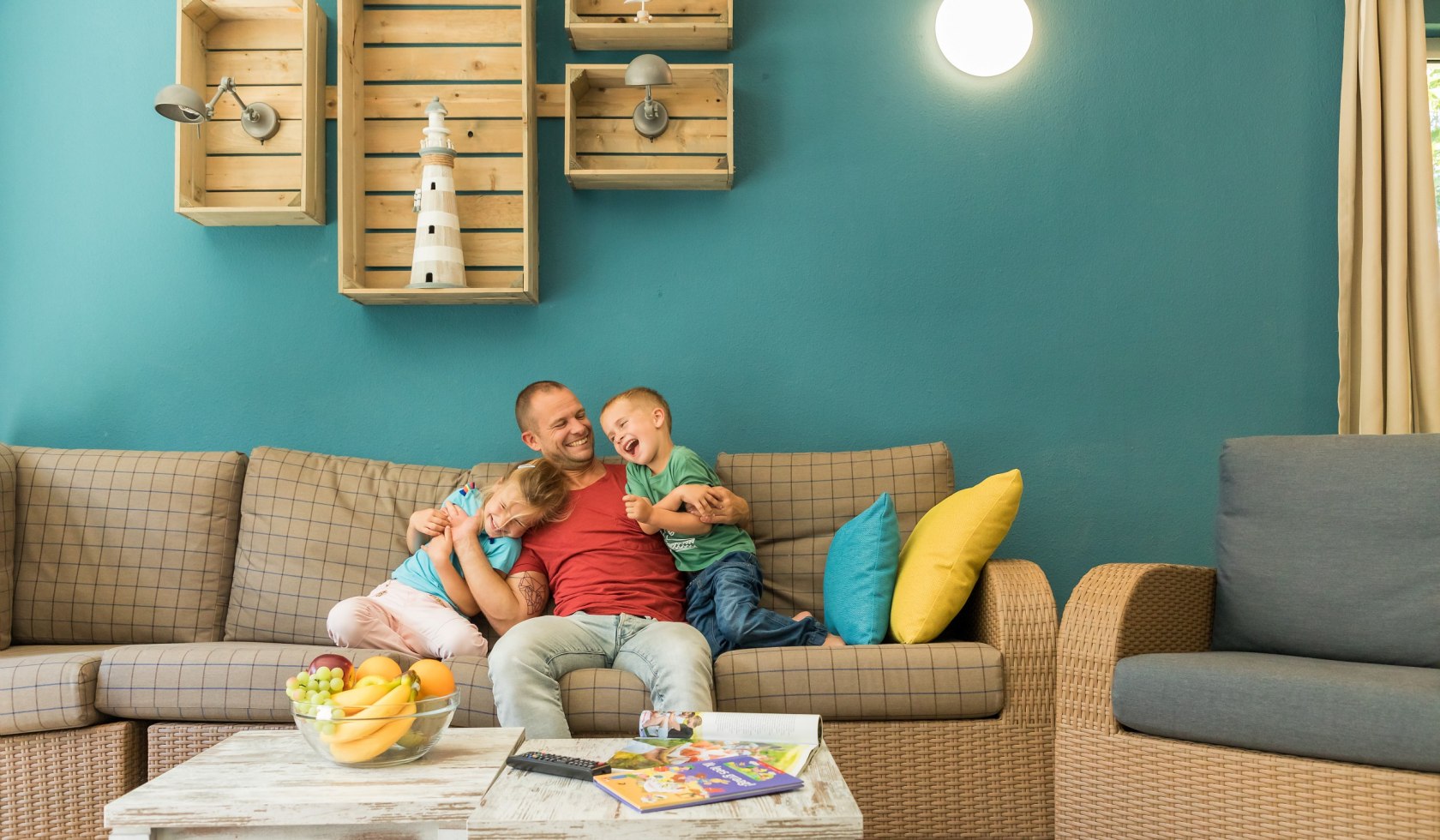 Vader knuffelt zijn twee kinderen op de bank in het vakantiehuis., © Center Parcs