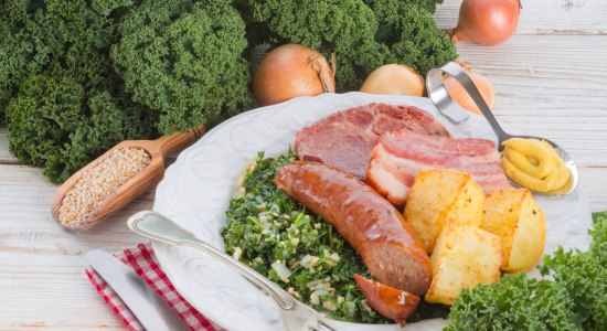 Het bord is gevuld met boerenkool, pinkel, aardappelen en gerookt varkensvlees., © Fotolia - Dzinnik Darius