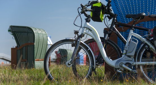 Ebikes leunen op een strandstoel, © Cuxland-Tourismus / Bernd Otten