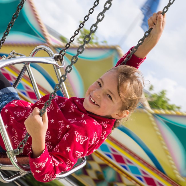 Een meisje heeft plezier in de kettingcarrousel, © Fotolia / Stefanie B.