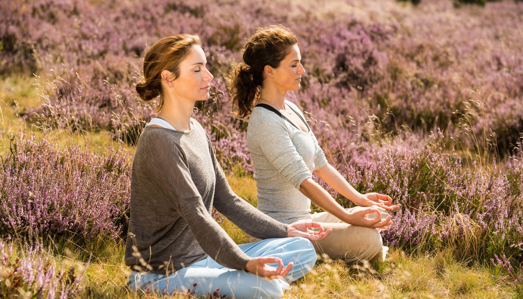 Twee vrouwen die yoga doen in de bloeiende Lüneburger Heide, © Lüneburger Heide GmbH / Dominik Ketz