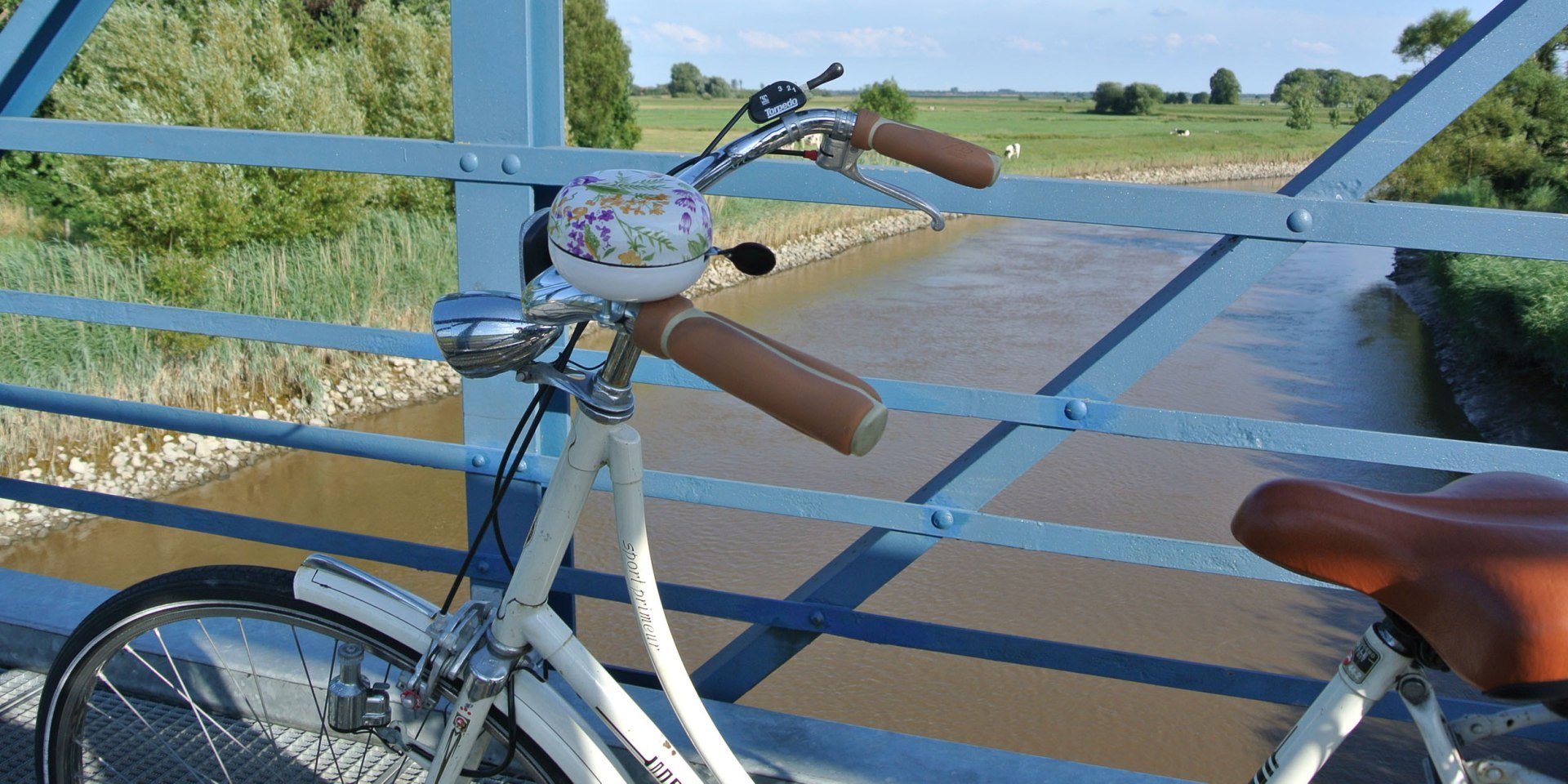 Uitzicht vanaf de Amdorf-brug op de voorgrond een fiets, © Ostfriesland Tourismus GmbH / www.ostfriesland.de Uitzicht vanaf de Amdorf-brug op de voorgrond een fiets, © Ostfriesland Tourismus GmbH / www.ostfriesland.de