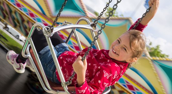 Een meisje heeft plezier in de kettingcarrousel, © Fotolia / Stefanie B.