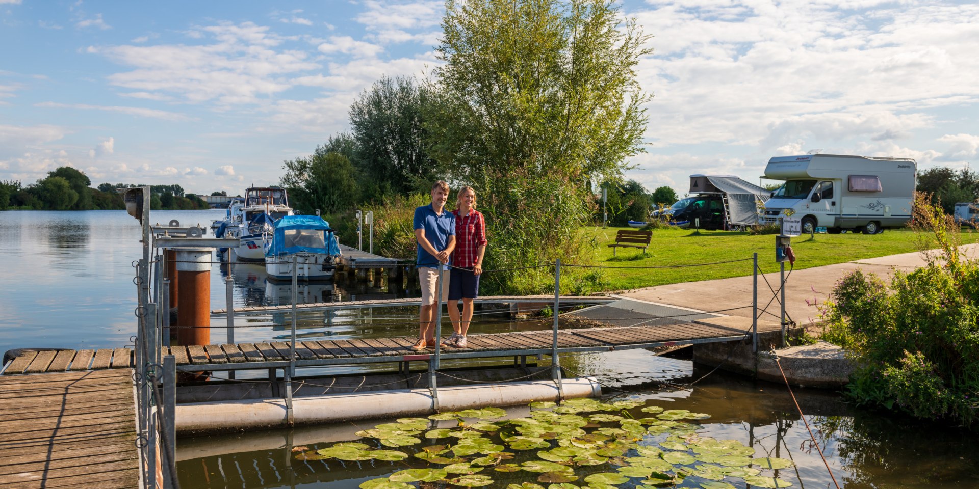 Een echtpaar staat op een steiger aan de rivier de Weser, op de achtergrond een camperplaats, © TMN / Markus Tiemann