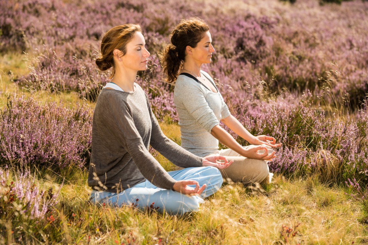 Twee vrouwen die yoga doen in de bloeiende Lüneburger Heide, © Lüneburger Heide GmbH / Dominik Ketz Twee vrouwen die yoga doen in de bloeiende Lüneburger Heide, © Lüneburger Heide GmbH / Dominik Ketz