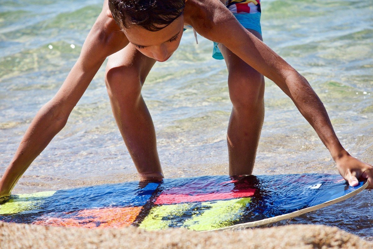 Jongen met surfplank op het strand, © Luisella Planeta Leoni